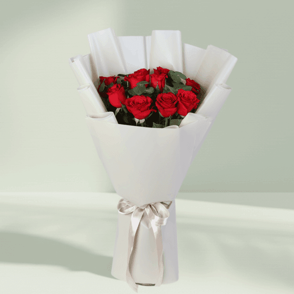 Bouquet of red roses and green foliage in a crisp white wrap with a satin ribbon.