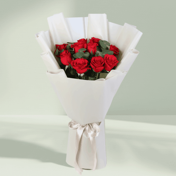 Bouquet of red roses and green foliage in a crisp white wrap with a satin ribbon.