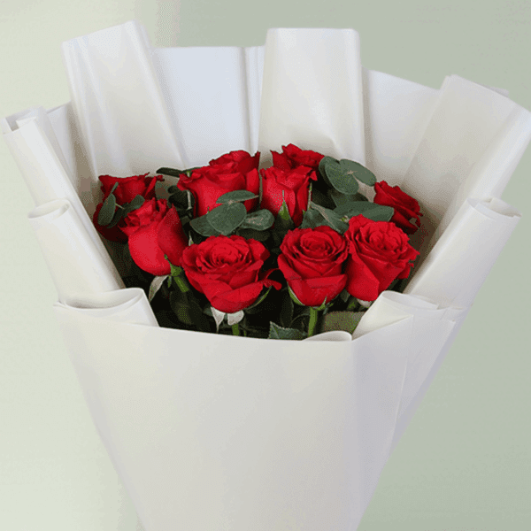 Bouquet of red roses and green foliage in a crisp white wrap with a satin ribbon.