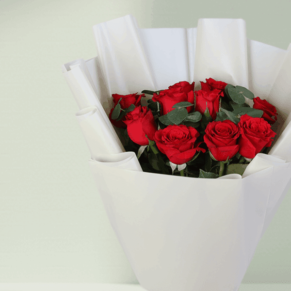Bouquet of red roses and green foliage in a crisp white wrap with a satin ribbon.