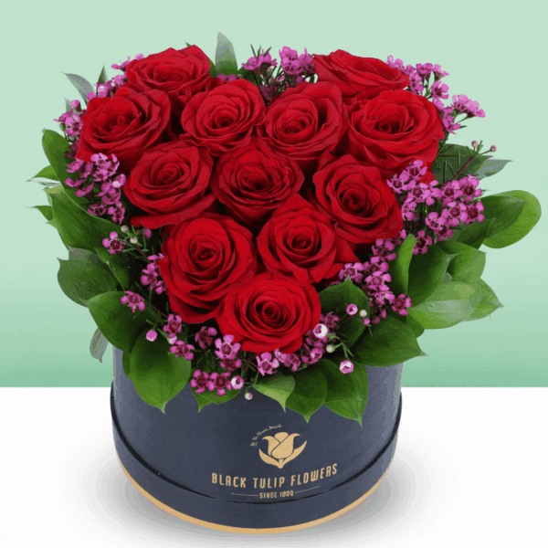 red-roses-purple-fillers-box (2) A black box featuring red roses in heart shape with purple filler flowers and green foliage.
