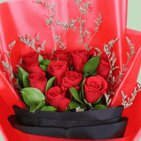 A bouquet of red roses with green foliage and delicate filler stems, wrapped in red and black, finished with a black ribbon.