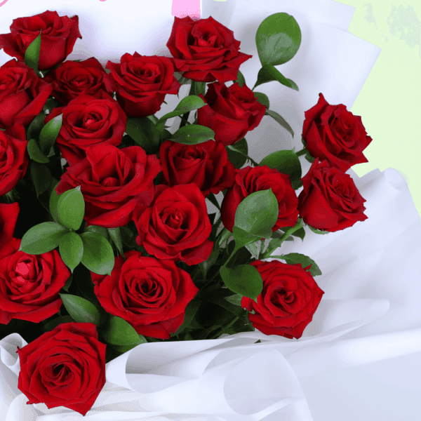 Red hand-tied rose bouquet placed on a white table with soft fabric wrap and a message note