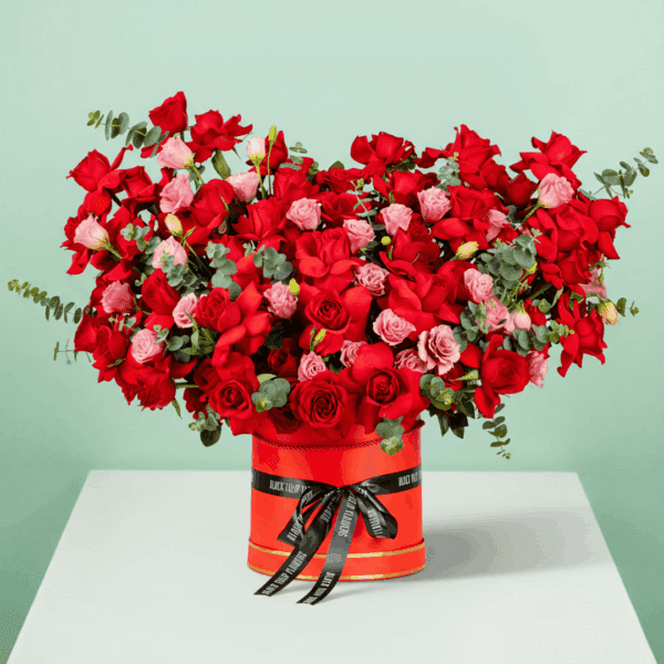 A striking floral arrangement featuring flowers all elegantly arranged in a round red box to symbolize fiery love and romance