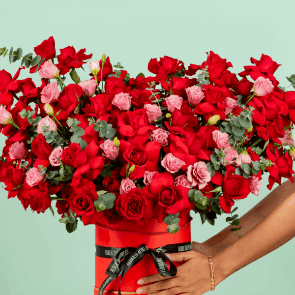 A striking floral arrangement featuring flowers all elegantly arranged in a round red box to symbolize fiery love and romance