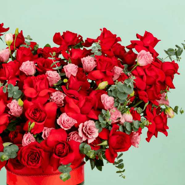 A striking floral arrangement featuring flowers all elegantly arranged in a round red box to symbolize fiery love and romance