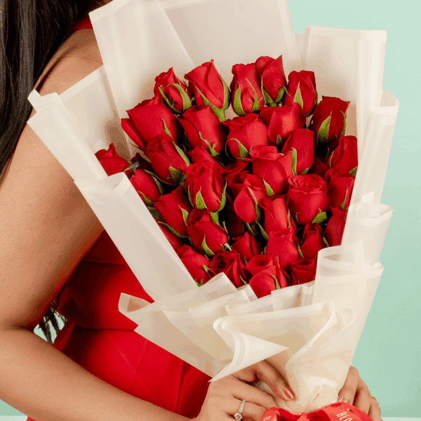 Woman in a red dress holding a Valentine’s bouquet of 30 fresh red roses, wrapped in elegant Korean-style flower sheets and finished with a red satin ribbon.