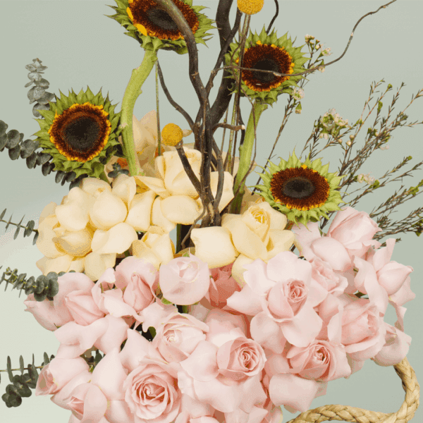 Beautiful sunflower and rose flower arrangement with crespedia, eucalyptus, wax flowers, and curly salix styled in a clear glass vase.