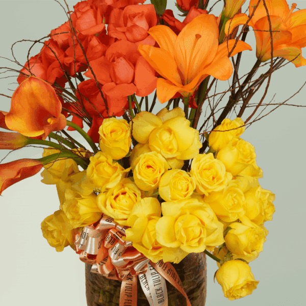 The Saffron Surge (1) Luxury tiered premium flower arrangement featuring yellow roses and orange lilies.