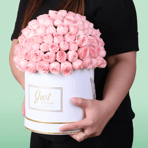 White round box filled with neatly arranged pink roses with a Mother’s Day topper placed on top, premium floral gift arrangement for Mom