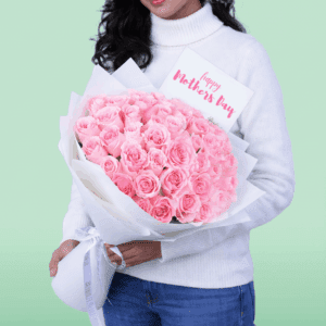 Hand-tied rose bouquet wrapped in non-woven paper with a small message card attached, styled as a Mother’s Day floral gift
