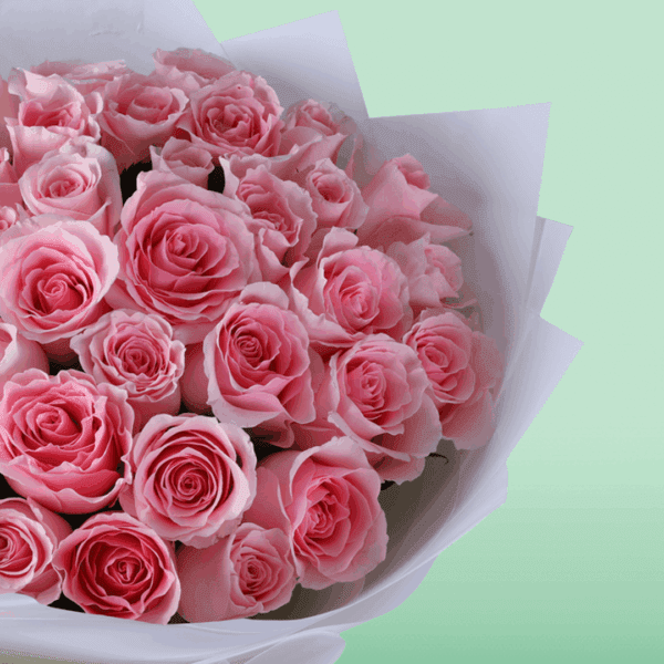 Hand-tied rose bouquet wrapped in non-woven paper with a small message card attached, styled as a Mother’s Day floral gift