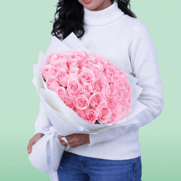 Hand-tied rose bouquet wrapped in non-woven paper with a small message card attached, styled as a Mother’s Day floral gift