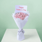 Roses arranged in a bouquet with soft non-woven wrapping with a white ribbon and decorative presentation
