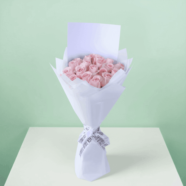 Roses arranged in a bouquet with soft non-woven wrapping with a white ribbon and decorative presentation