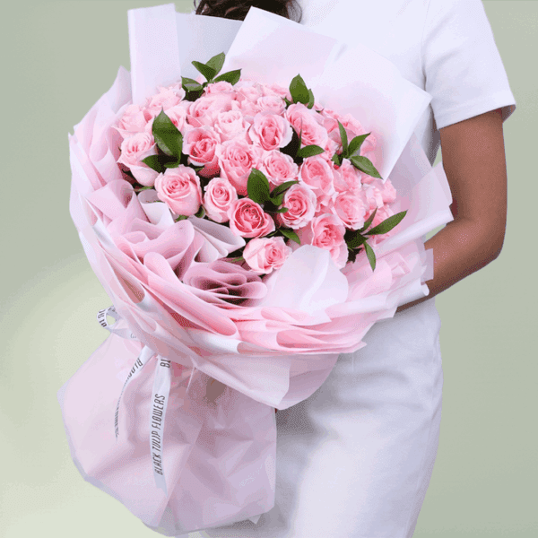 Floral arrangement of roses and spray roses in non-woven wrap with a message card styled for Mother’s Day gifting