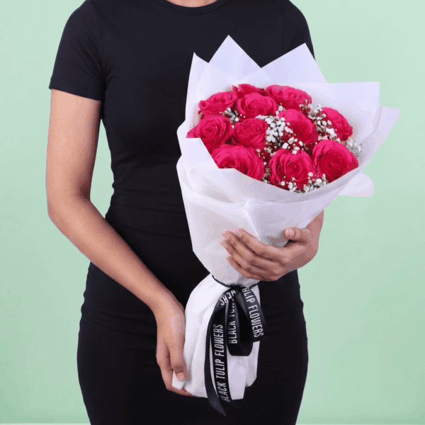 Bouquet of 20 pink roses wrapped in non-woven paper with green leaves visible, arranged neatly in a hand-tied style.