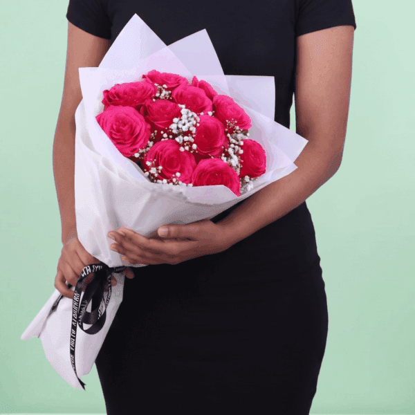 Bouquet of 20 pink roses wrapped in non-woven paper with green leaves visible, arranged neatly in a hand-tied style.