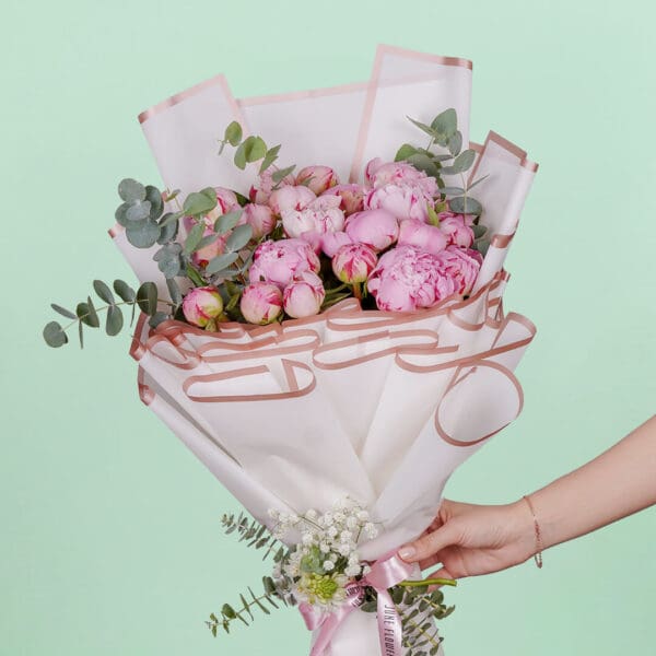 Luxury bouquet of 20 blooming pink peonies and green foliage beautifully hand-tied and presented in elegant Korean-style white wrapping paper.