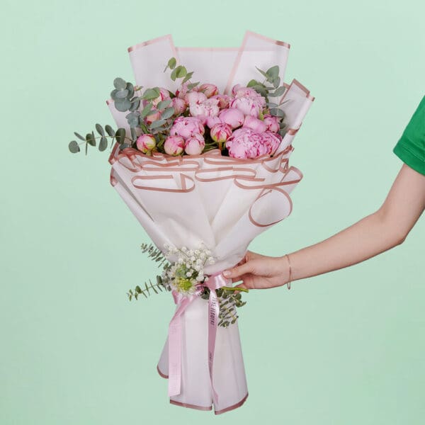 Luxury bouquet of 20 blooming pink peonies and green foliage beautifully hand-tied and presented in elegant Korean-style white wrapping paper.