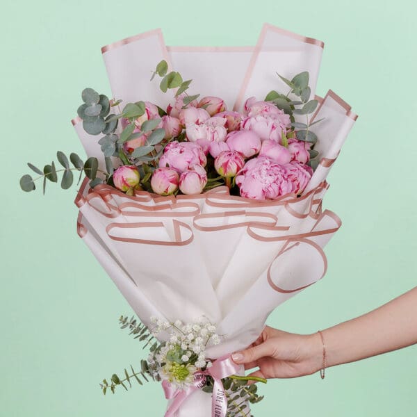 Luxury bouquet of 20 blooming pink peonies and green foliage beautifully hand-tied and presented in elegant Korean-style white wrapping paper.
