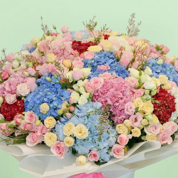 Premium pastel flower bouquet with hydrangeas, roses, eustomas, and wax flowers in a luxurious floral arrangement.