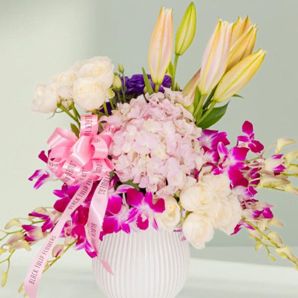 Luxury white ceramic vase arrangement featuring a mix of hydrangeas, orchids, roses, lilies, and fresh greenery designed for elegant gifting.