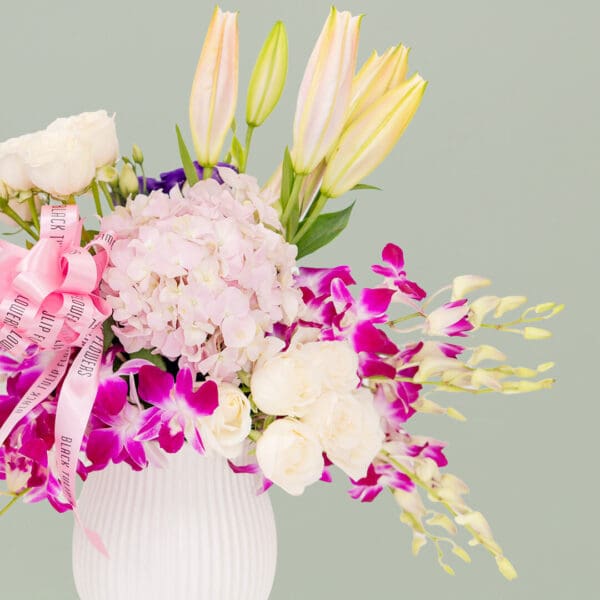 Luxury white ceramic vase arrangement featuring a mix of hydrangeas, orchids, roses, lilies, and fresh greenery designed for elegant gifting.