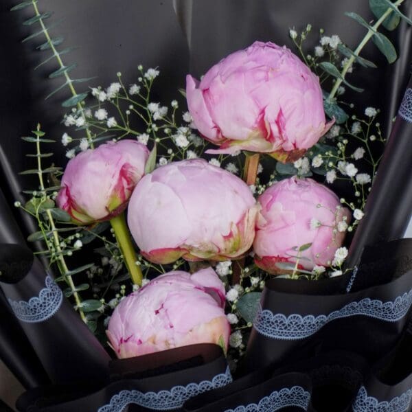 The arrangement features 5 fresh pink peony stems beautifully arranged and wrapped in premium Korean-style flower wrapping black sheets.