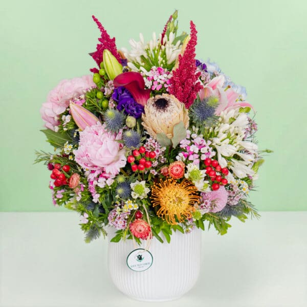 The arrangement featuring 35–40 stems of protea, hydrangea, amaranthus, pincushion, lilies, and assorted exotic flowers put together in a premium ceramic vase.