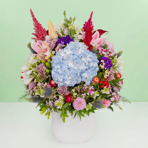The arrangement featuring 35–40 stems of protea, hydrangea, amaranthus, pincushion, lilies, and assorted exotic flowers put together in a premium ceramic vase.