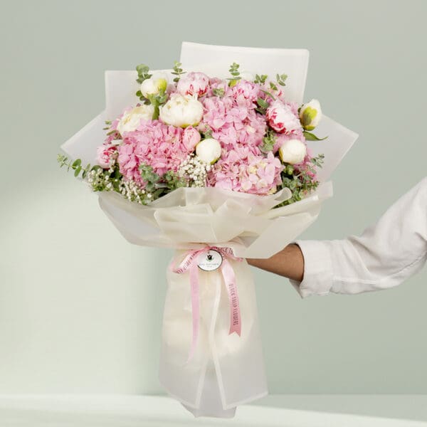 15-stem pink flower bouquet featuring peonies, hydrangeas, and fresh eucalyptus elegantly wrapped in Korean-style white wrapping sheets.