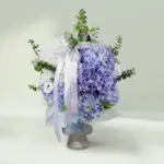 Grand bouquet of mixed seasonal flowers featuring roses, hydrangeas, cymbidium, and eustoma in an elegant round vase.