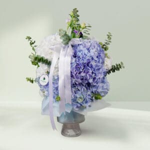Grand bouquet of mixed seasonal flowers featuring roses, hydrangeas, cymbidium, and eustoma in an elegant round vase.