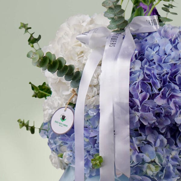 Grand bouquet of mixed seasonal flowers featuring roses, hydrangeas, cymbidium, and eustoma in an elegant round vase.